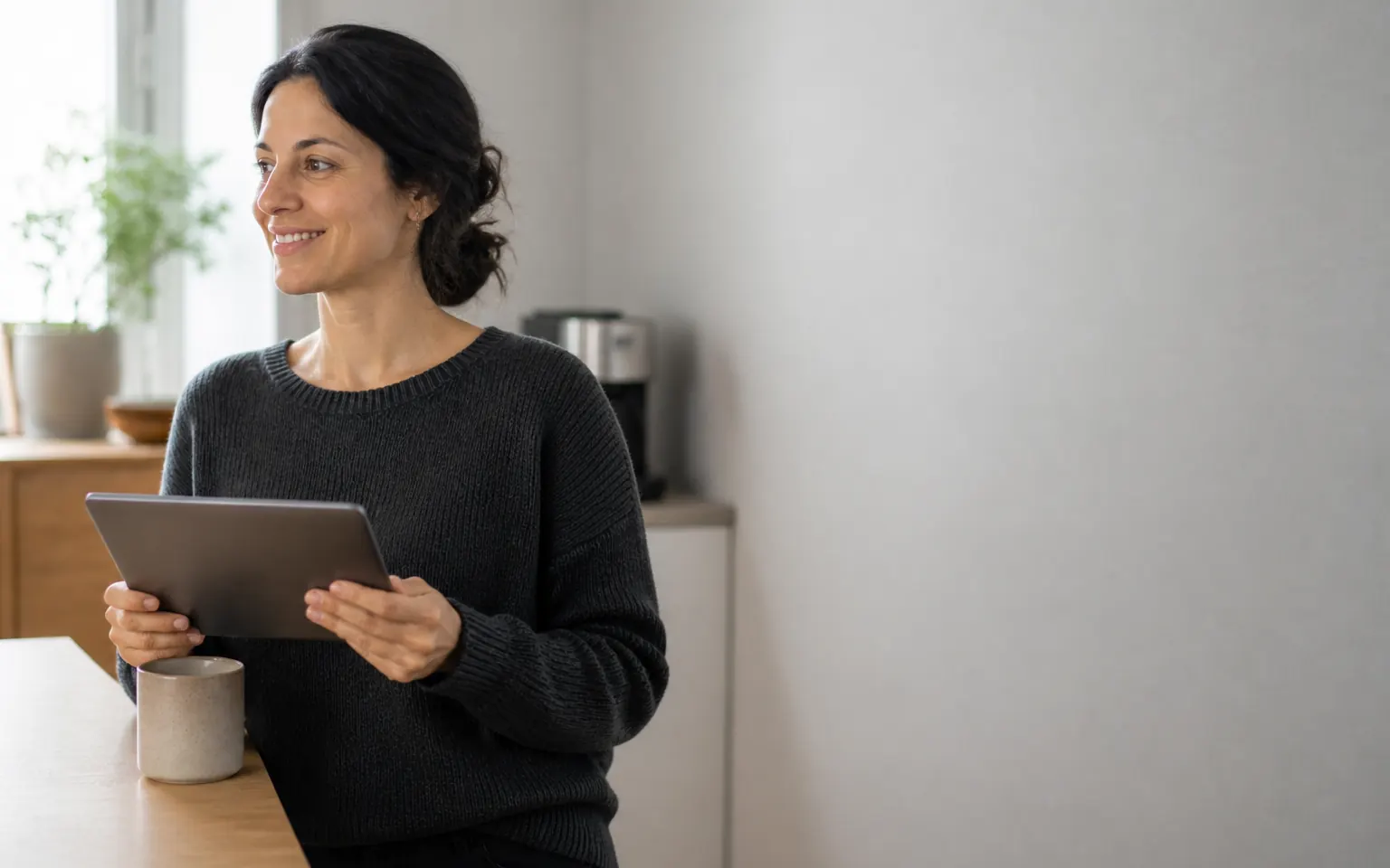Recruiting lead glancing at a tablet over coffee while applicants are reviewed